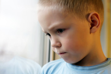 Sad boy at the window, loneliness and depression