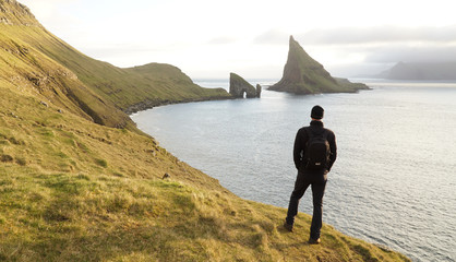Hiker at the Drangarnir Sea Stack Mountain and Ocean Landscape in the Faroe Islands, Denmark.