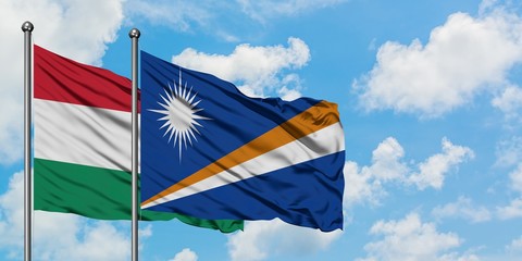 Hungary and Marshall Islands flag waving in the wind against white cloudy blue sky together. Diplomacy concept, international relations.