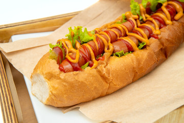 Hot dog with salad and cucumbers with tomato ketchup and mustard on white background. Tasty and beautiful fast food on a light back.