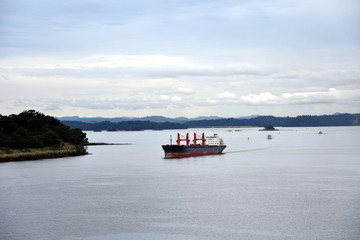 Landscape of the Gatun Lake on a cloudy day, Panama Canal. Cargo ships sailing toward Gatun Locks. 