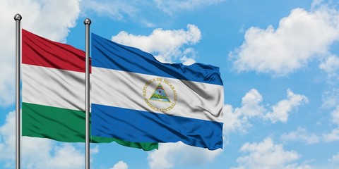 Hungary and Nicaragua flag waving in the wind against white cloudy blue sky together. Diplomacy concept, international relations.