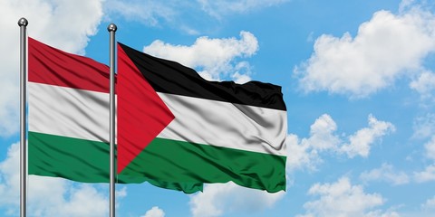 Hungary and Palestine flag waving in the wind against white cloudy blue sky together. Diplomacy concept, international relations.