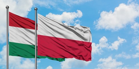 Hungary and Poland flag waving in the wind against white cloudy blue sky together. Diplomacy concept, international relations.