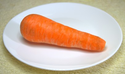 Carrots. One. Whole for cooking different dishes. On a white plate. Vegetables. Food.