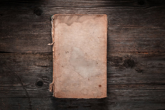 Closed book on vintage wooden background.  Old book on the wooden table. Closed book with empty cover laying on wooden table. - Powered by Adobe