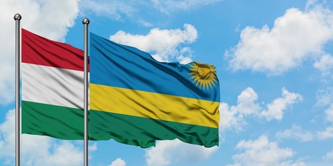 Hungary and Rwanda flag waving in the wind against white cloudy blue sky together. Diplomacy concept, international relations.