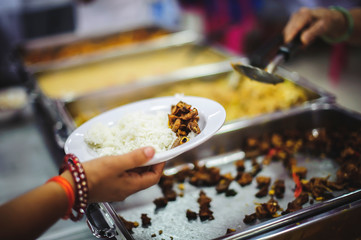 The concept of food needs in society : The recipient's hand holds a dish to request free charity food from a volunteer.