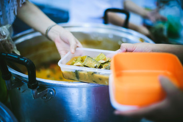 The concept of food needs in society : The recipient's hand holds a dish to request free charity food from a volunteer.