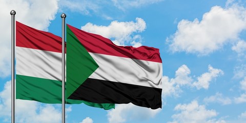 Hungary and Sudan flag waving in the wind against white cloudy blue sky together. Diplomacy concept, international relations.