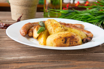 Grilled sausages with herb potatoes and ketchup, tasty summer picnic dish, sausages on skewers a dark wooden background