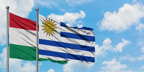 Hungary and Uruguay flag waving in the wind against white cloudy blue sky together. Diplomacy concept, international relations.