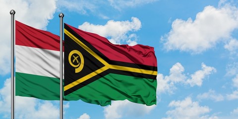 Hungary and Vanuatu flag waving in the wind against white cloudy blue sky together. Diplomacy...