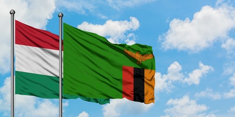 Hungary and Zambia flag waving in the wind against white cloudy blue sky together. Diplomacy concept, international relations.