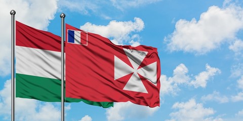 Hungary and Wallis And Futuna flag waving in the wind against white cloudy blue sky together....