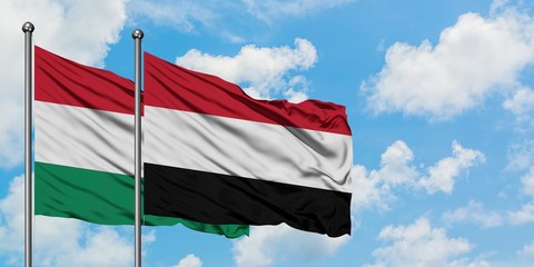 Hungary and Yemen flag waving in the wind against white cloudy blue sky together. Diplomacy concept, international relations.