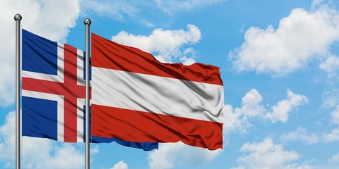 Iceland and Austria flag waving in the wind against white cloudy blue sky together. Diplomacy...