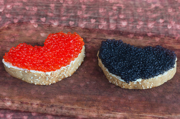 Sandwiches with caviar in the shape of a heart on a cutting Board. Overlay bokeh in the shape of a heart.