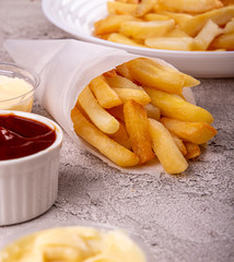 paper conus of french fries chips potato and sauces on gry concrete background. copy space