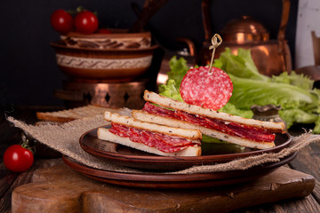 Heep of sandwiches toasted bread and salami on wooden table. fast food unhealthy concept