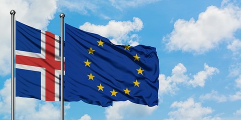 Iceland and European Union flag waving in the wind against white cloudy blue sky together....