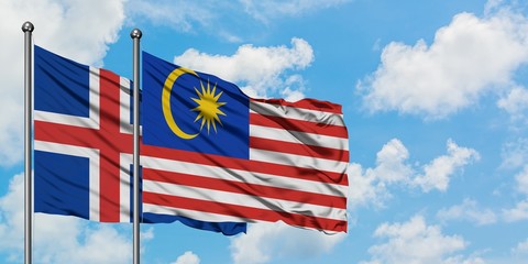 Iceland and Malaysia flag waving in the wind against white cloudy blue sky together. Diplomacy concept, international relations.