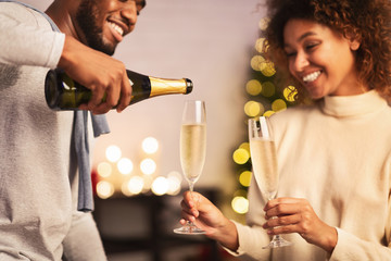 Husband pouring champagne, celebrating Christmas with wife