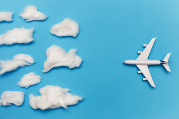 Toy plane on blue background flies to overcast. Flat lay of bad weather and transportation and travel concept