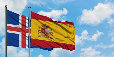 Iceland and Spain flag waving in the wind against white cloudy blue sky together. Diplomacy concept, international relations.