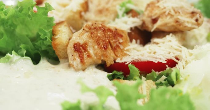 Fresh Caesar salad with chicken, vegetables, eggs and chopped lettuce covered with delicious sauce and parmesan cheese. Shot in 4k UHD