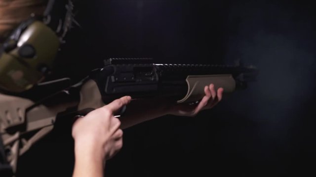Over the Shoulder Slow-Motion View of Woman Shooting Pump-Action Shotgun at Shooting Range With Propper Trigger Discipline and Safety Precaution