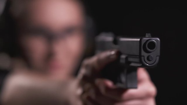Rack Focus of Woman Holding Pistol in Shooting Range With Propper Trigger Discipline and Safety Precaution