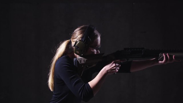 Side View of Woman Shooting Pump-Action Shotgun in Shooting Range in Slow Motion With Smoking Shell Ejecting