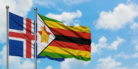 Iceland and Zimbabwe flag waving in the wind against white cloudy blue sky together. Diplomacy...