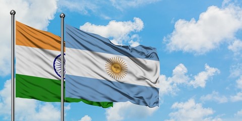 India and Argentina flag waving in the wind against white cloudy blue sky together. Diplomacy concept, international relations.