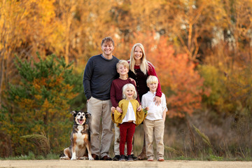 Happy Young Family of Parents and Children and Pet Dog Outside on Summy Fall Day.