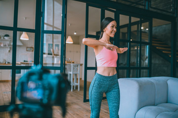 Smiling blogger doing warm up before filming morning tutorial