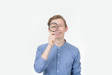 Smiling tennager with magnifying glass on white background. Curious Teenager with Magnifying Glass Isolated on the White Background.