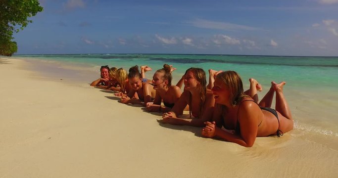 Group of girls lying on line over white beach sunbath and tan on sunshine of summer day in Antigua