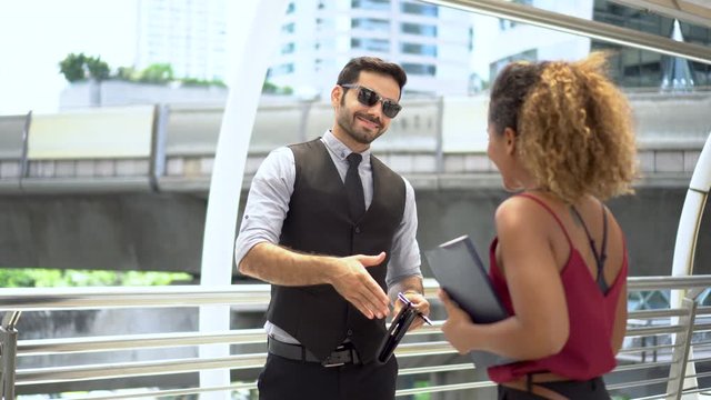 group of two young multi ethnic business people meeting and signing document paperwork together outside office. happy African American woman employee  with manager outdoors. shaking hands and talking