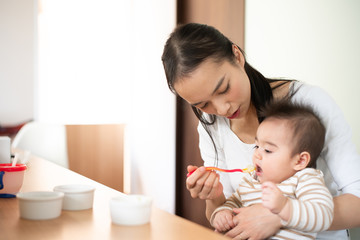 Mother feeding baby food to her baby