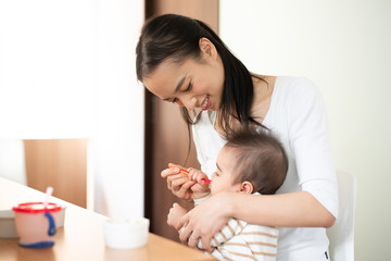 Obraz na płótnie Canvas Mother feeding baby food to her baby