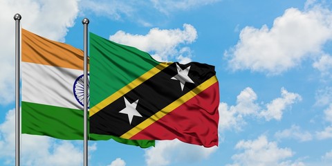 India and Saint Kitts And Nevis flag waving in the wind against white cloudy blue sky together. Diplomacy concept, international relations.