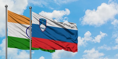 India and Slovenia flag waving in the wind against white cloudy blue sky together. Diplomacy concept, international relations.