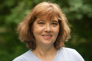 Portrait of beautiful middle-aged woman in Park in summer. Good looking 60 year old European