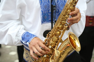 Obraz premium Folklore artist play saxophone wearing beautiful traditional costume.