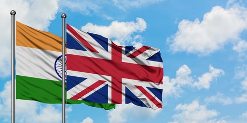 India and United Kingdom flag waving in the wind against white cloudy blue sky together. Diplomacy concept, international relations.