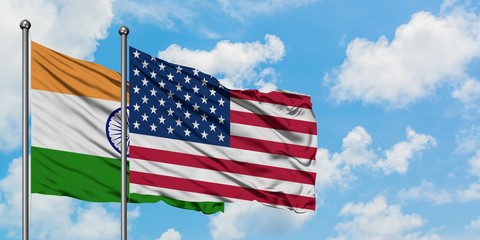 India and United States flag waving in the wind against white cloudy blue sky together. Diplomacy concept, international relations.