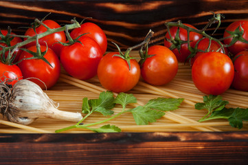 Raw pasta and cherry tomatoes, garlic and parsley in wooden box