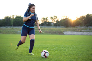 young woman kicks a soccer ball with her foot. Not sporty girl, on the green grass, football field